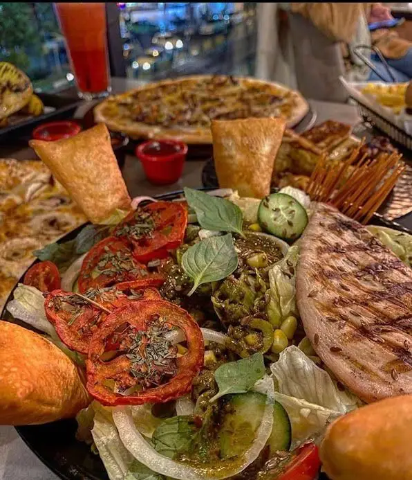 تجربه لذت‌بخش در رستوران ایتالیایی باپوک: میز پر از پیتزای داغ، سالاد تازه با مرغ گریل، نوشیدنی و پیش‌غذا. غذای عالی.