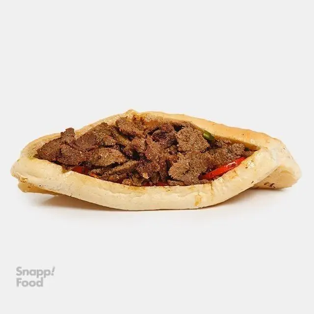 ساندویچ گوشت لذیذ و پرحجم (کباب ترکی یا شاورما) در نان تازه و طلایی از ساندویچی نشاط، گزینه‌ای عالی برای تجربه یک غذای فست فود خوشمزه.