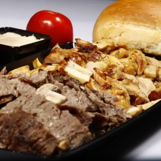 یک سینی غذای خوشمزه و کامل از ساندویچی نشاط شامل برش‌های کباب گوشت و مرغ، همراه سیب‌زمینی سرخ کرده، سس و نان تازه. مناسب سفارش فست فود.