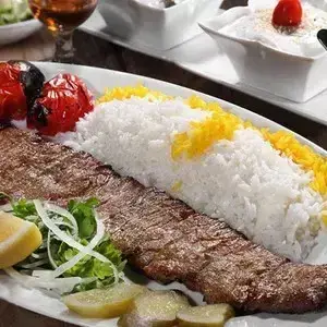 کباب برگ آبان با برنج زعفرانی خوش عطر، گوجه کبابی، پیاز و لیمو. لذت غذای سنتی ایرانی در رستوران کباب آبان.