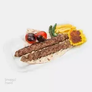 کباب کوبیده آبان: یک پرس غذای اصیل ایرانی شامل دو سیخ کباب کوبیده لذیذ، گوجه کبابی، ته دیگ زعفرانی و سیب‌زمینی سرخ کرده.