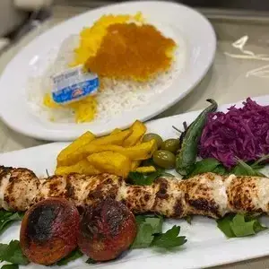 تصویری از جوجه کباب باکیفیت کباب ابان، همراه با پلو زعفرانی، سیب زمینی، زیتون و دورچین تازه. تجربه طعم اصیل غذای ایرانی.