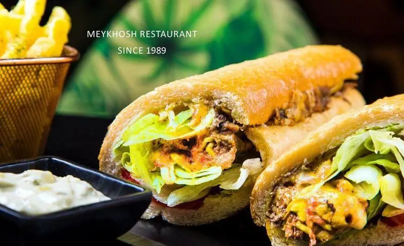 تصویری جذاب از ساندویچ‌های تازه و لذیذ رستوران و پیتزا میخوش با سیب‌زمینی و سس. تجربه طعم بی‌نظیر فست فود.