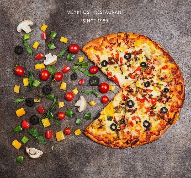 تصویری زیبا از پیتزای گوشت و سبزیجات رستوران و پیتزا میخوش، با ترکیبات تازه مانند فلفل، گوجه، زیتون و قارچ برای تجربه‌ای دلپذیر.