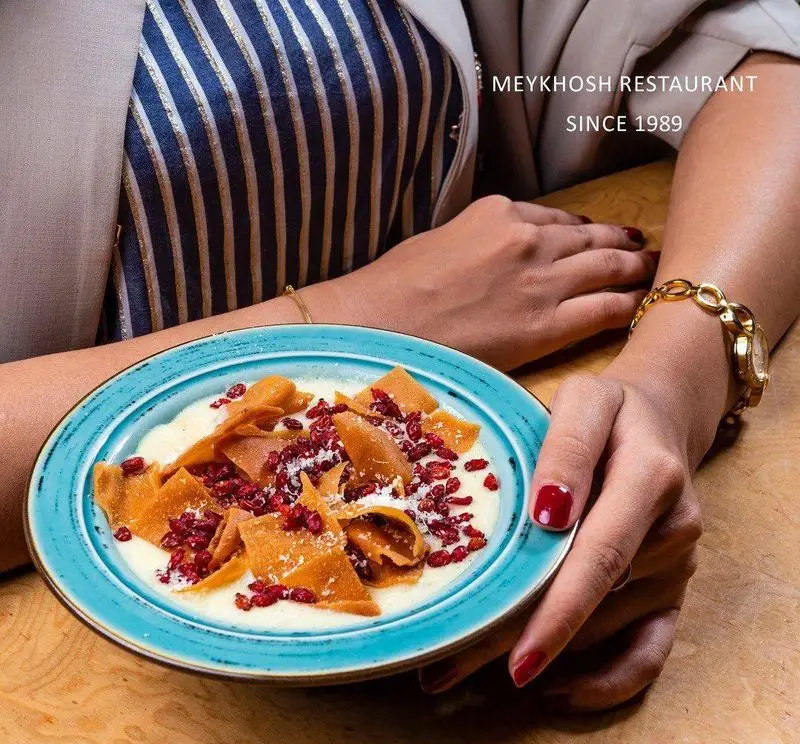 غذای سنتی ایرانی در رستوران میخوش. کاسه آبی پر از دسر یا غذای سنتی با نان برشته و زرشک. تجربه دلنشین در رستوران میخوش.