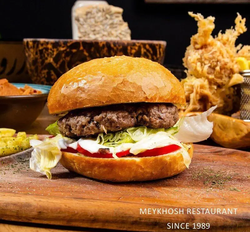 همبرگر ویژه و لذیذ رستوران میخوش، آماده سرو با نان تازه، گوشت آبدار، کاهو، گوجه و سس سفید، از مجموعه رستوران و پیتزا میخوش.