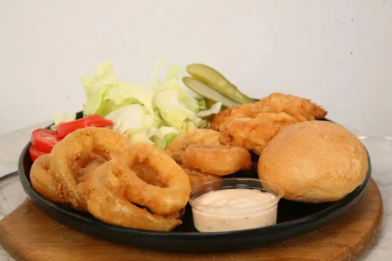 عکس یک وعده فست فود کامل کافه رستوران توژی شامل پیاز سوخاری، ناگت مرغ، نان برگر، کاهو، گوجه و سس مخصوص.