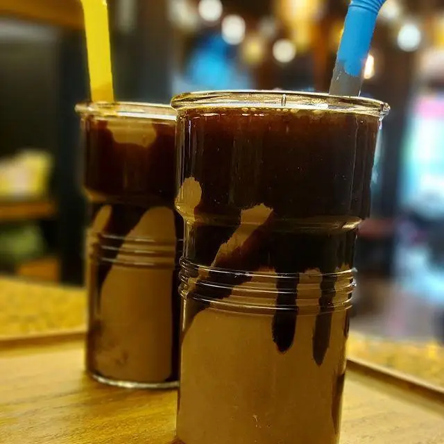 دو لیوان شیک شکلاتی (یا قهوه) با سس شکلات در کافه رستوران توژی، نوشیدنی‌های دلپذیر برای تجربه لذت‌بخش و لحظاتی شیرین.