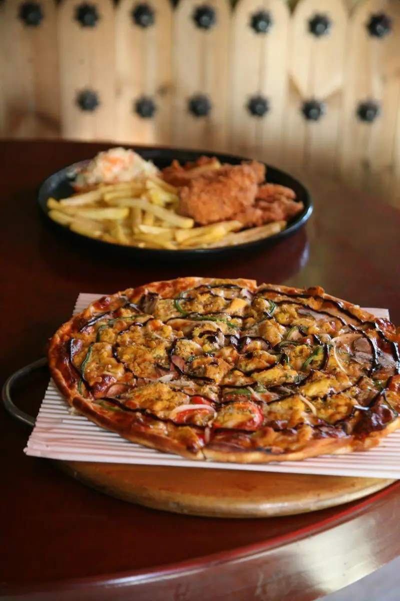 پیتزای لذیذ و مرغ سوخاری با سیب زمینی سرخ کرده در کافه رستوران توژی. تجربه‌ای خوشمزه از غذاهای متنوع برای مشتریان.