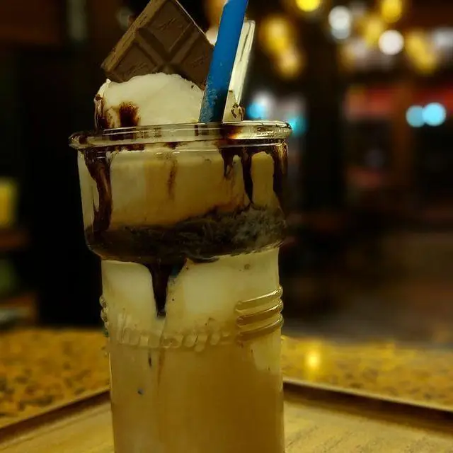 میلگ شیک شکلاتی لایه ای با بستنی، تزئین شکلات و سس، یک نوشیدنی سرد و خوشمزه در کافه رستوران توژی. لذت طعم های کافه‌ای.