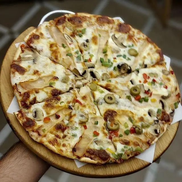 پیتزا لذیذ کافه رستوران توژی با ترکیبی از سس سفید، قارچ تازه، زیتون سبز و فلفل دلمه‌ای رنگی. انتخابی عالی برای یک وعده خاص.