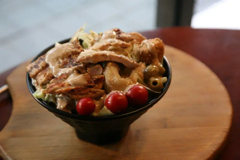 تصویری جذاب از سالاد سزار مرغ گریل شده و فوق العاده لذیذ با سس مخصوص، گوجه گیلاسی و زیتون در کافه رستوران توژی.