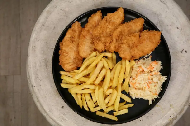 تصویر یک بشقاب کامل از فیله مرغ سوخاری ترد و خوش طعم با سیب زمینی سرخ کرده و سالاد کلم مخصوص کافه رستوران توژی.