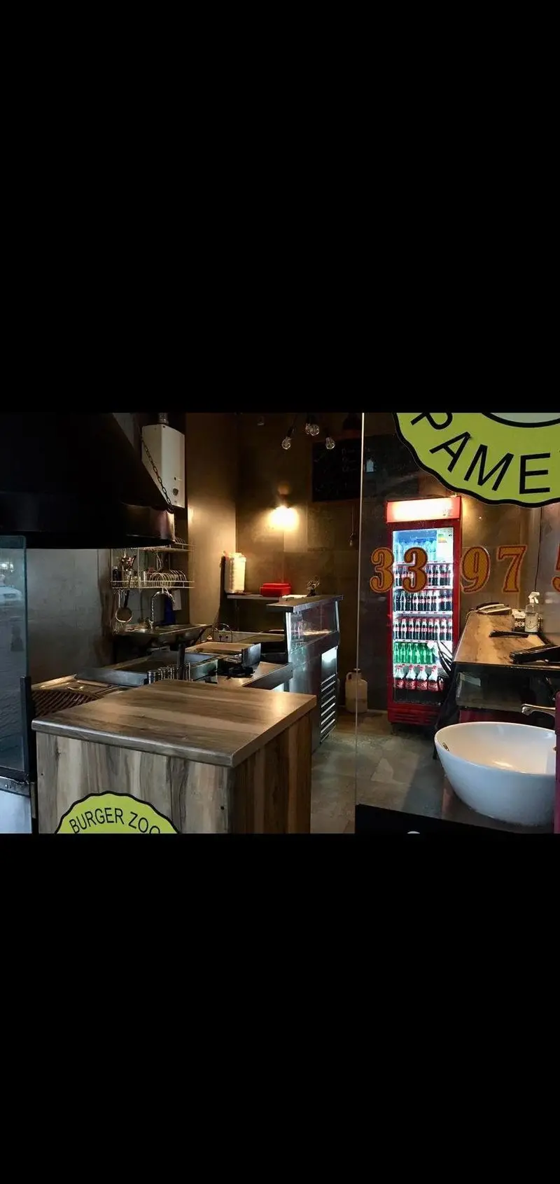 تصویر داخلی آشپزخانه حرفه‌ای و پیشرفته برگر زغالی پامنار، شامل کانتر سرو، یخچال نوشیدنی و محیطی تمیز برای آماده‌سازی غذا.