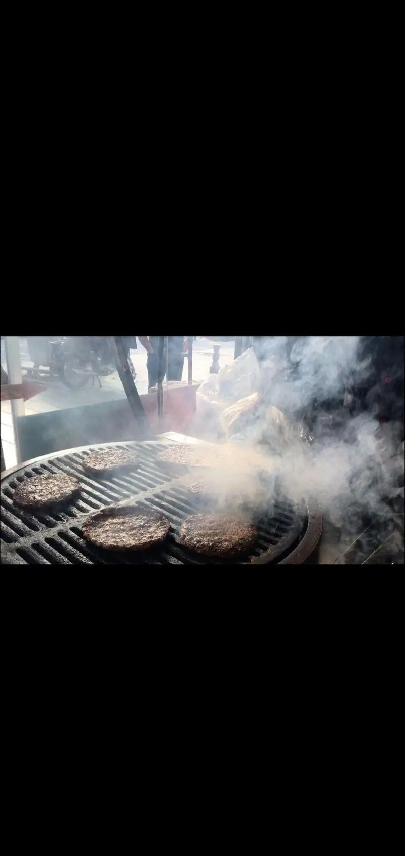 برگر زغالی پامنار در حال کباب شدن روی منقل زغالی با دود خوش عطر، آماده سرو به مشتریان در فضای باز و محیطی دلنشین.