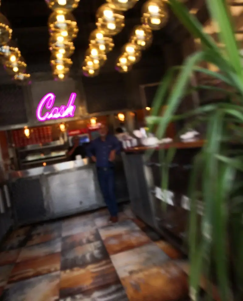 فضای داخلی فست فود سه سار با دکوراسیون مدرن، لوسترهای کروی زیبا، کانتر پذیرش و پرسنل. محیطی گرم و دلپذیر برای مشتریان.