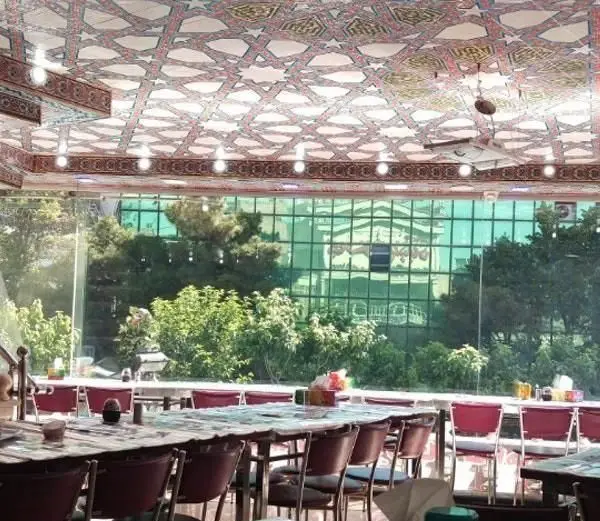 محیط دلنشین و دلباز رستوران ایرانیان با سقف باشکوه طرح اسلامی، چیدمان میز و صندلی آماده پذیرایی و چشم‌انداز طبیعی سبز