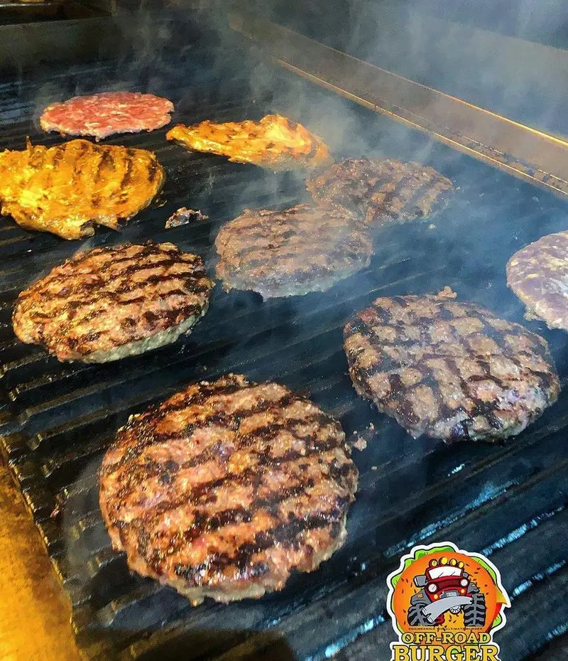 همبرگرهای آبدار و جوجه کباب لذیذ در حال گریل شدن روی توری داغ آفرود برگر. آماده‌سازی یک وعده غذای خوشمزه و تازه.