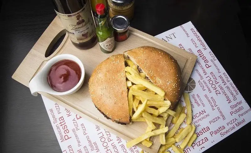 یک پیتزا یا نان ویژه رستوران ایتالیایی ژولی پر از سیب زمینی سرخ کرده داغ، کچاپ، سس و نوشیدنی. لذت غذای ایتالیایی و فست فود.