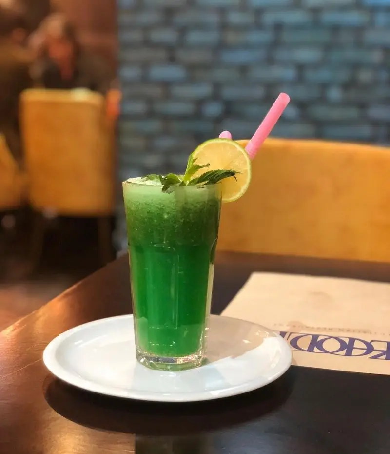 نوشیدنی سبز تازه و خنک (اسموتی یا آبمیوه) با نعنا، لیمو و نی صورتی در رستوران ایتالیایی ژولی، تجربه‌ای دلنشین و باطراوت.