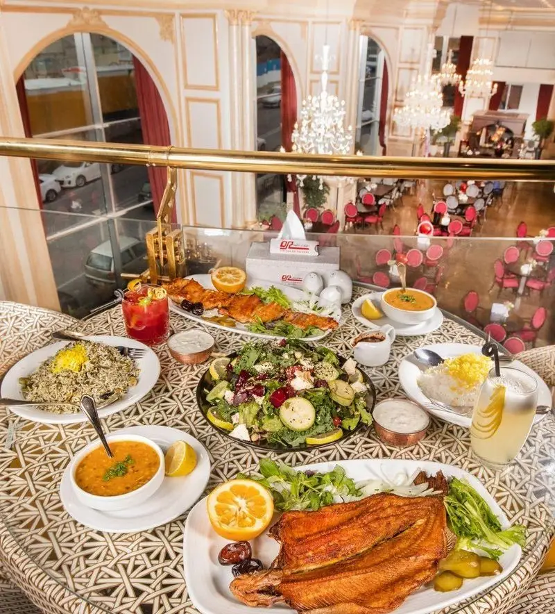 میز مملو از غذاهای متنوع چلوکبابی ارکیده: کباب، سبزی پلو، سالاد فصل، سوپ و نوشیدنی‌های تازه در رستورانی مجلل و چشم‌نواز.