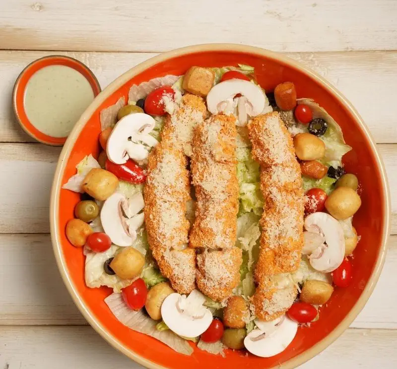 سالاد سزار ویژه فست فود ریحان شامل مرغ سوخاری ترد، کاهو، قارچ، گوجه گیلاسی، زیتون و پنیر پارمزان با سس سبز.