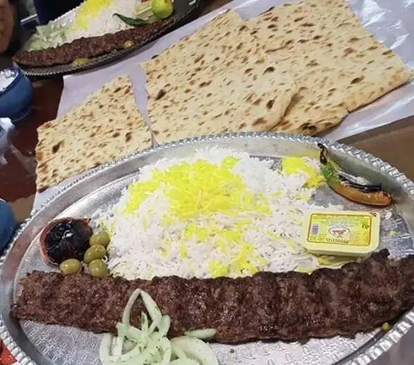 چلو کباب کوبیده اصیل بناب با برنج زعفرانی، گوجه، پیاز و نان تازه در رستوران کباب ناب بناب، یک غذای خوشمزه سنتی ایرانی.