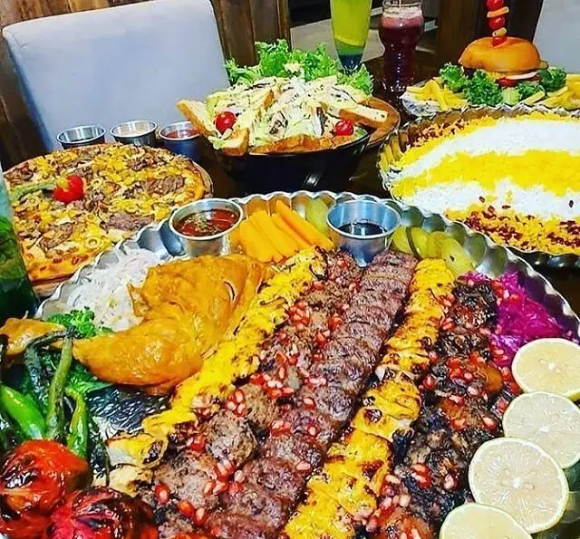 سینی بزرگ غذای کافه و سفره خانه نارونی: کباب کوبیده، جوجه کباب، مرغ، پلو زعفرانی، پیتزا، سالاد سزار و برگر