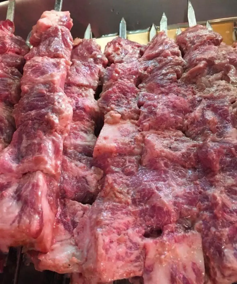 سیخ های کباب گوشت تازه، آبدار و با رگه‌های چربی عالی آماده پخت در جگر سرای ۱۱۰، لذت کباب اصیل ایرانی.