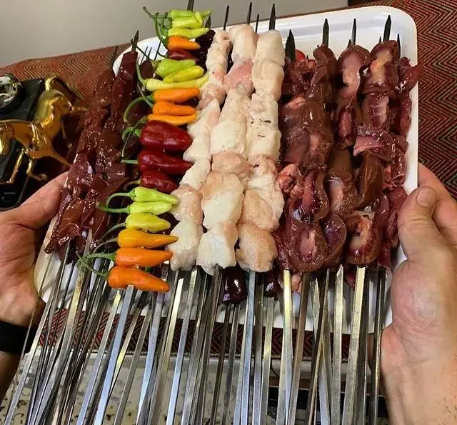 سینی بزرگ کباب جگر تازه و دنبه در جگر سرای ۱۱۰ با فلفل‌های رنگی آماده برای پخت، یک تجربه خوشمزه ایرانی.