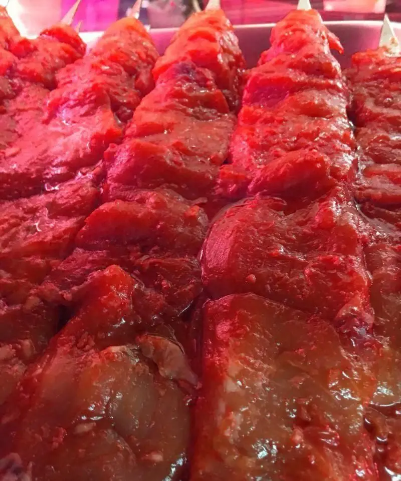 نمایی نزدیک از سیخ‌های جگر و دل کبابی مزه‌دار شده، آماده برای پخت در جگر سرای ۱۱۰. بهترین تجربه طعم کباب اصیل ایرانی.