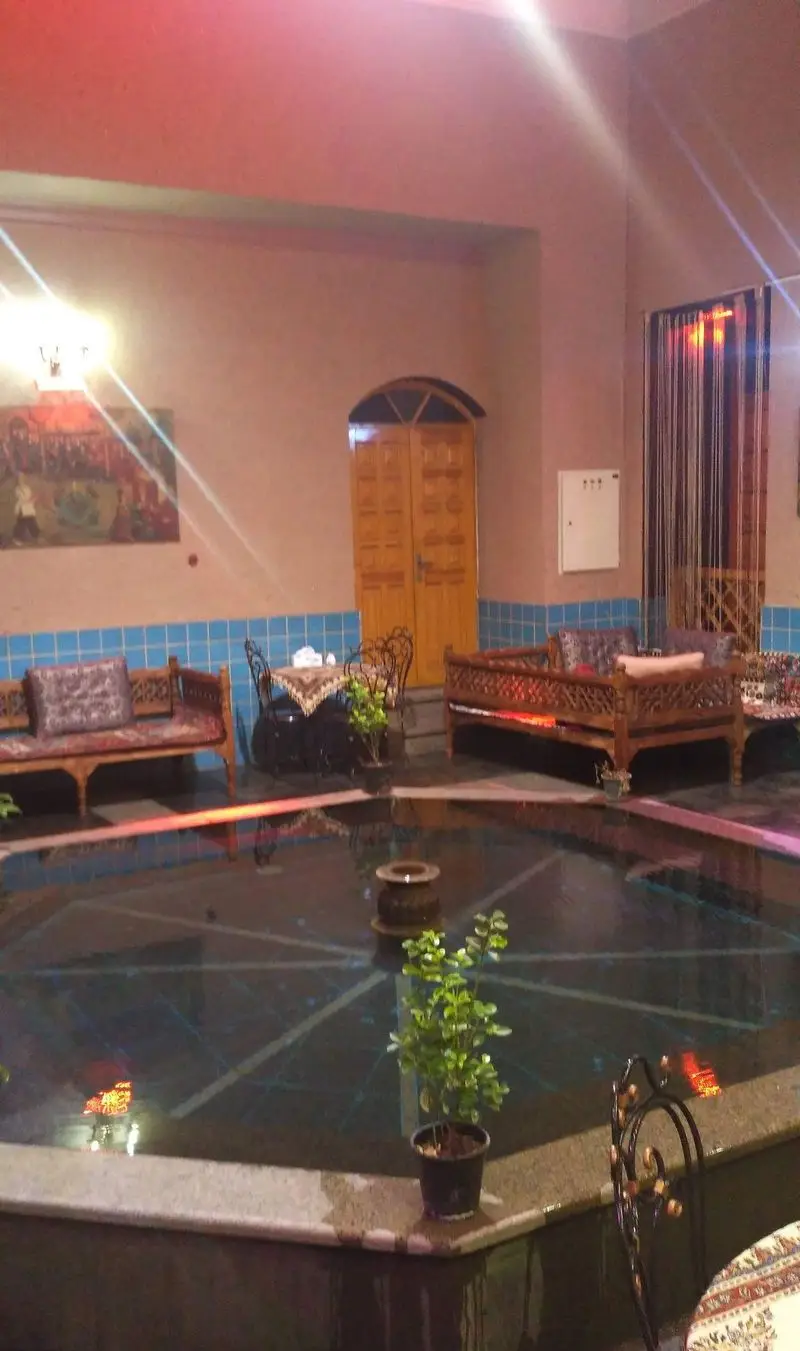 نمای داخلی رستوران اشراق با حوض مرکزی، تخت‌های چوبی سنتی، نورپردازی گرم و محیطی اصیل برای پذیرایی از مهمانان.