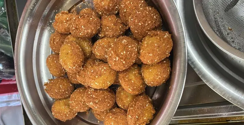 فلافل‌های خوشرنگ و طلایی بیروتی نیاوران، پوشیده از دانه‌های کنجد سفید، تازه از روغن بیرون آمده و آماده سرو.