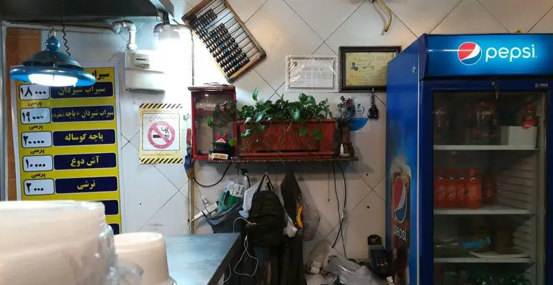 فضای داخلی طباخی سیرابی و شیردان دایی علی با منوی غذاها و قیمت‌ها، شامل سیراب شیردان، پاچه گوساله، آش دوغ و یخچال پپسی.