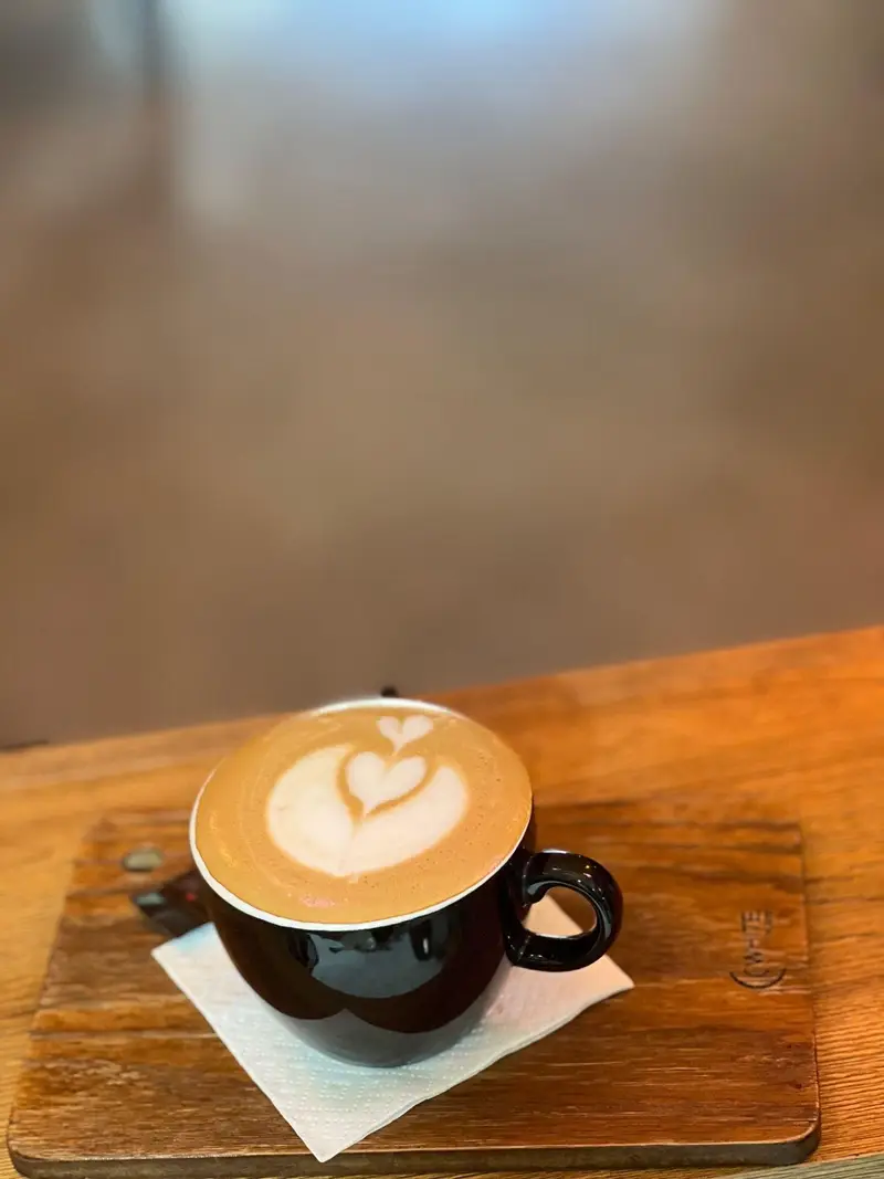 تصویر یک فنجان قهوه لاته آرت با طرح قلب روی تخته چوبی در کافه پارس. نوشیدنی گرم و دلپذیر برای تجربه ای لذت بخش.