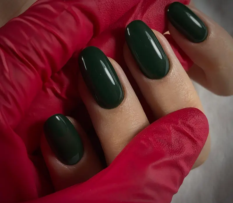 ناخن‌های زیبا و بلند به رنگ سبز یشمی براق و طرح بیضی، با کیفیت بالای خدمات مانیکور در سالن زیبایی کافه پارس.