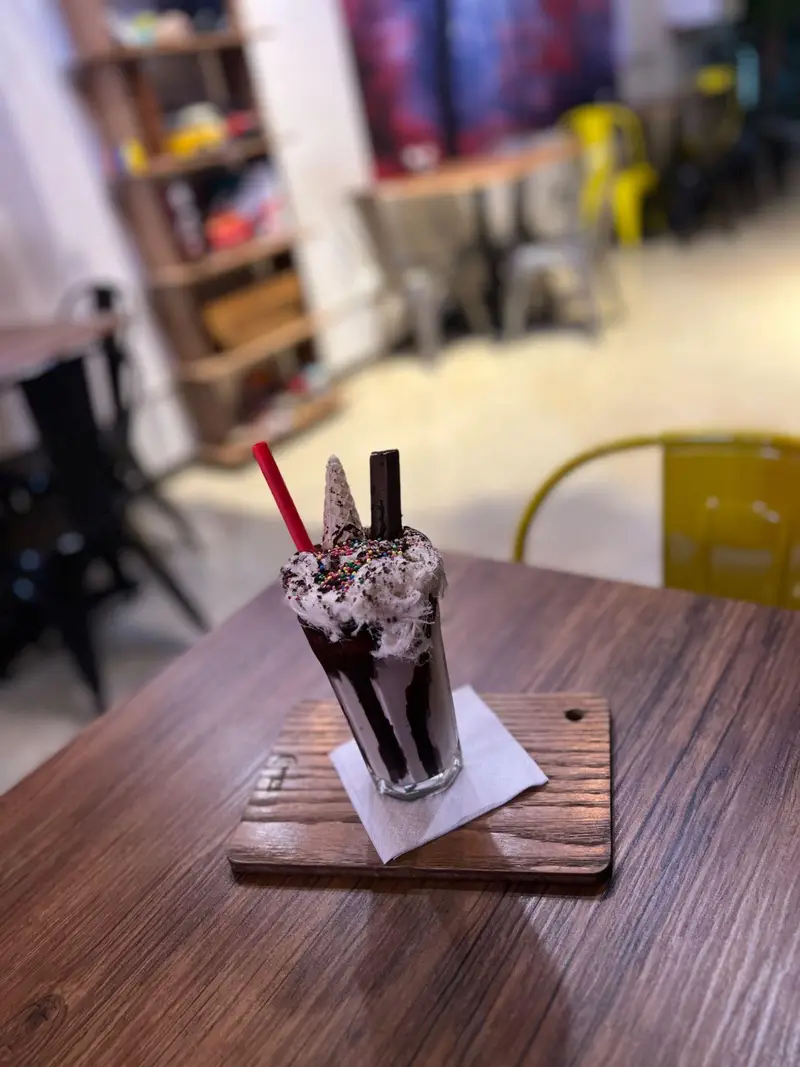 میلکشیک شکلاتی خوشمزه کافه پارس با خامه و اسپرینکل، گزینه‌ای عالی برای لذت بردن از فضای دلنشین کافه.