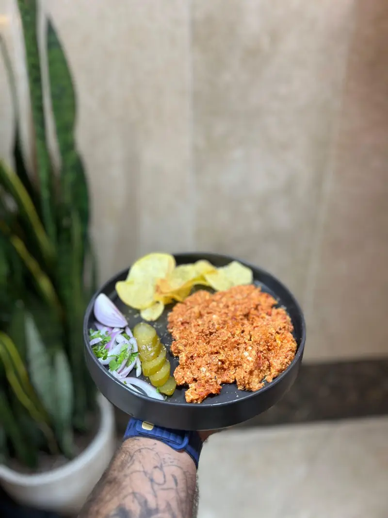 املت یا نیمرو محبوب و خوشرنگ کافه پارس به همراه چیپس، پیاز و خیارشور، که بر روی یک بشقاب سیاه شیک سرو شده است. تجربه‌ای لذیذ در کافه پارس.