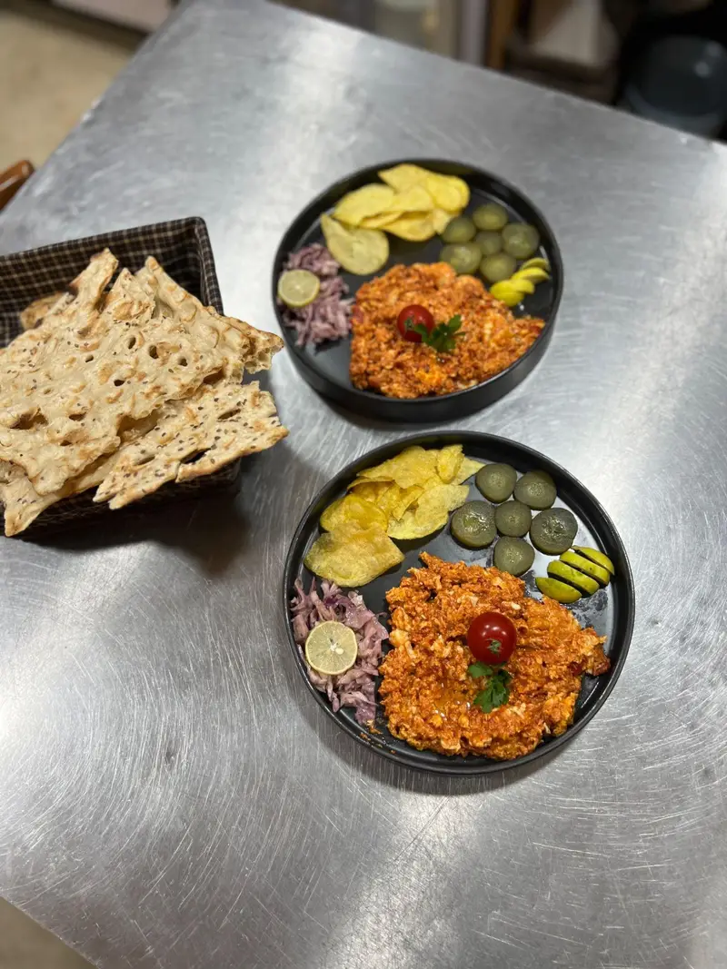 دو بشقاب املت گوجه فرنگی لذیذ کافه پارس با چیپس سیب زمینی، خیارشور، سالاد کلم قرمز و نان ترد؛ انتخابی عالی برای وعده غذایی.