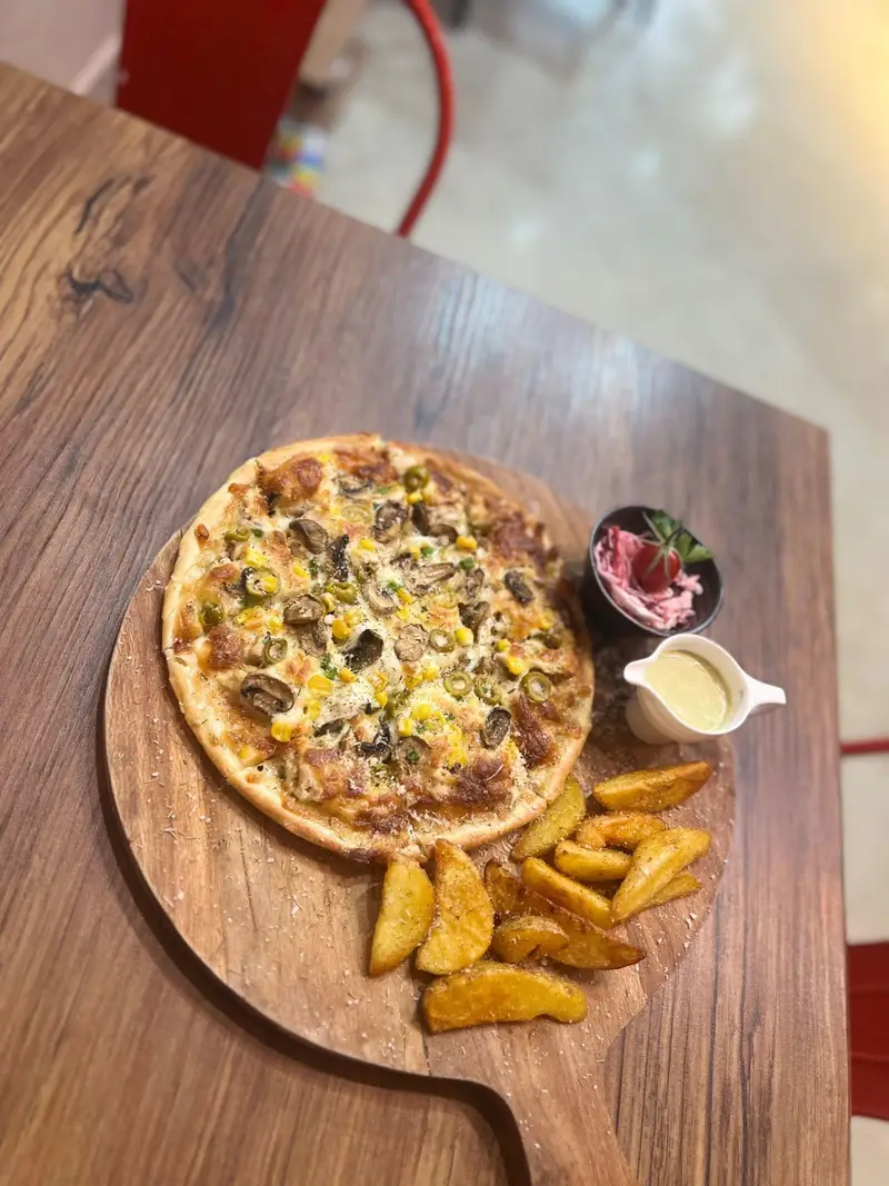 تصویر پیتزا قارچ، ذرت و زیتون به همراه سیب زمینی و سالاد تازه. غذای لذیذ منوی کافه پارس برای تجربه ای عالی.