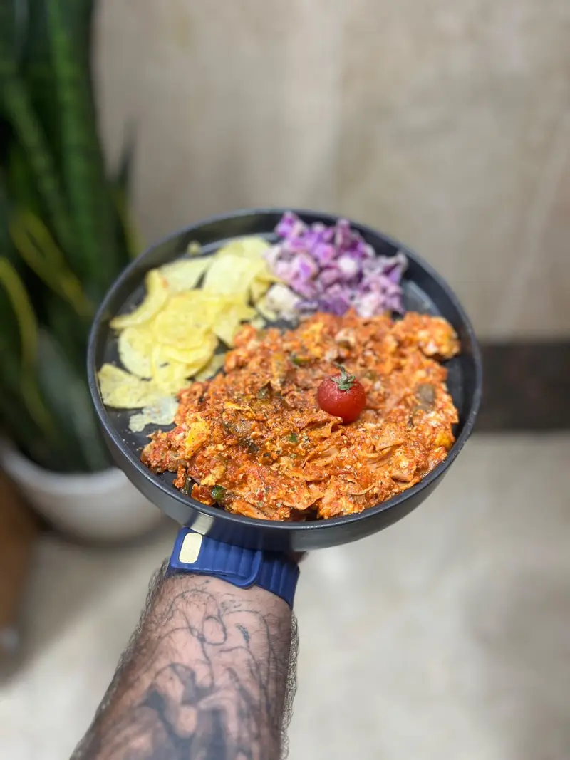 خوراک مخصوص و خوشمزه کافه پارس: املت و تخم مرغ با سس گوجه، سرو شده با چیپس و سالاد کلم بنفش. غذایی کامل و لذیذ.