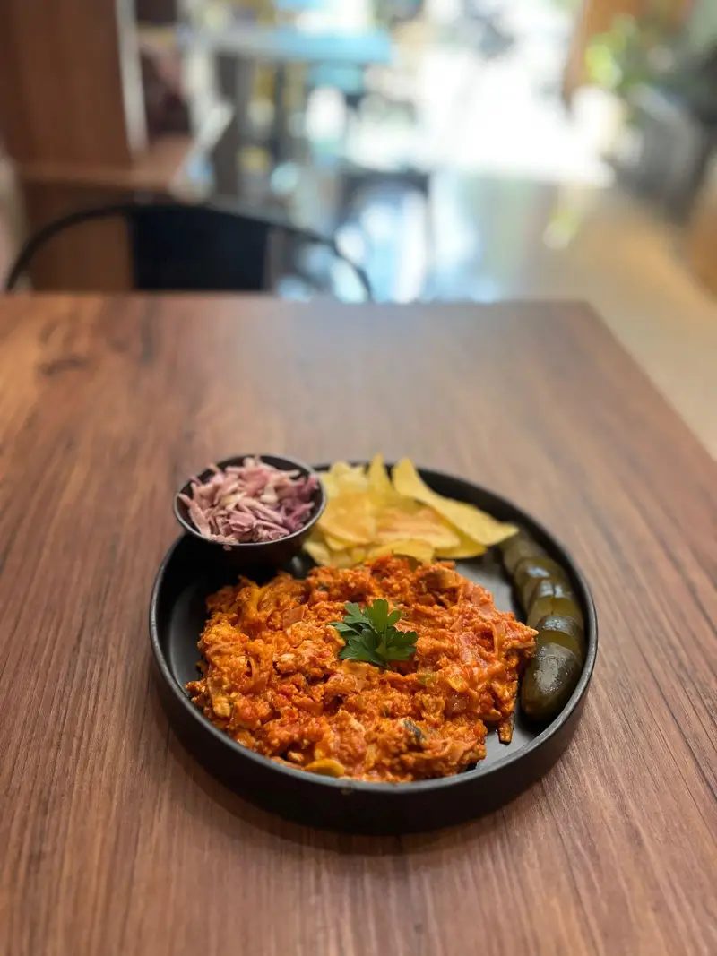 بشقاب لذیذ املت گوجه و تخم مرغ، چیپس، خیارشور و کلم قرمز در کافه پارس. تجربه‌ای دلنشین از طعم و فضای دنج.