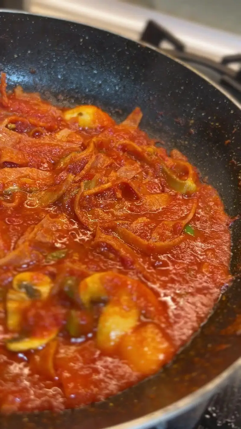 پخت سس گوجه فرنگی با قارچ و پیاز در تابه، آماده‌سازی غذای گرم و تازه برای منوی ویژه و خوشمزه کافه پارس.