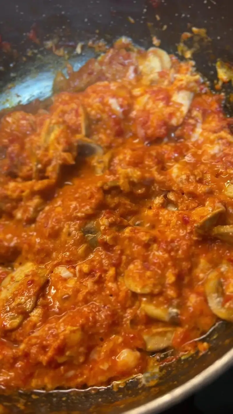 نمای نزدیک از غذای داغ و تازه، املت گوجه و تخم‌مرغ لذیذ در حال آماده‌سازی در آشپزخانه کافه پارس؛ انتخابی بی‌نظیر برای صبحانه یا برانچ.