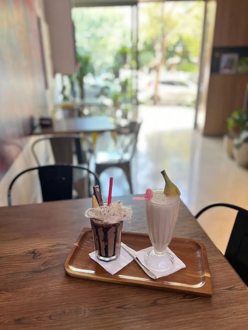 نمایی از میلک شیک شکلاتی و موز در کافه پارس، ارائه‌دهنده انواع نوشیدنی‌های سرد و گرم با دکوری مدرن و فضایی آرام.