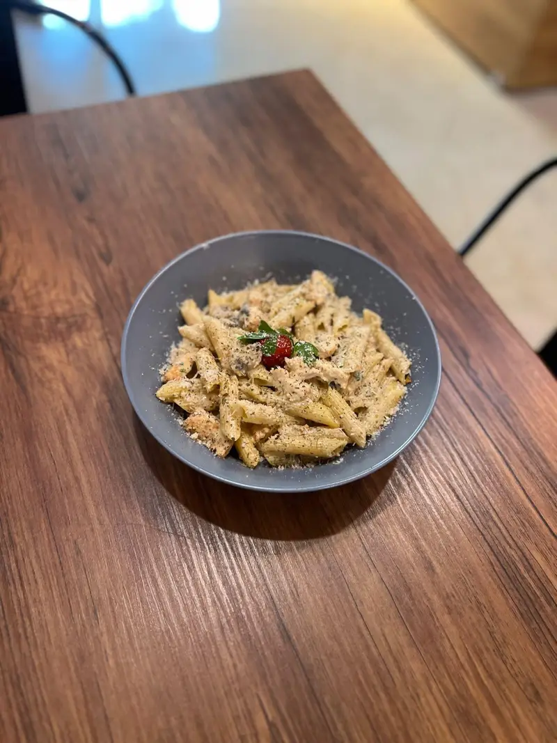 پاستا پنه لذیذ با سس مخصوص، پنیر پارمزان و تزیینات تازه در کاسه‌ای زیبا، بهترین گزینه از منوی غذایی کافه پارس.