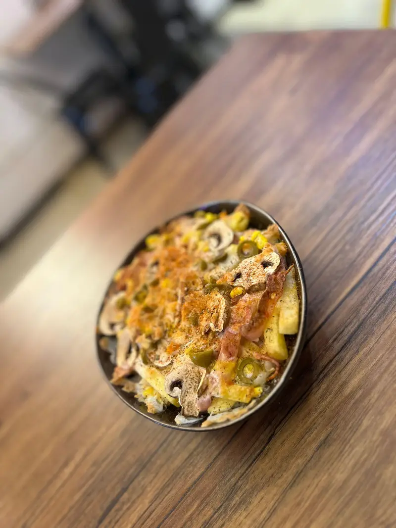 ظرفی از سیب زمینی سرخ کرده با قارچ، ذرت، پنیر و هالاپینو در کافه پارس. غذایی خوشمزه و پرطرفدار برای دوستداران فست فود.