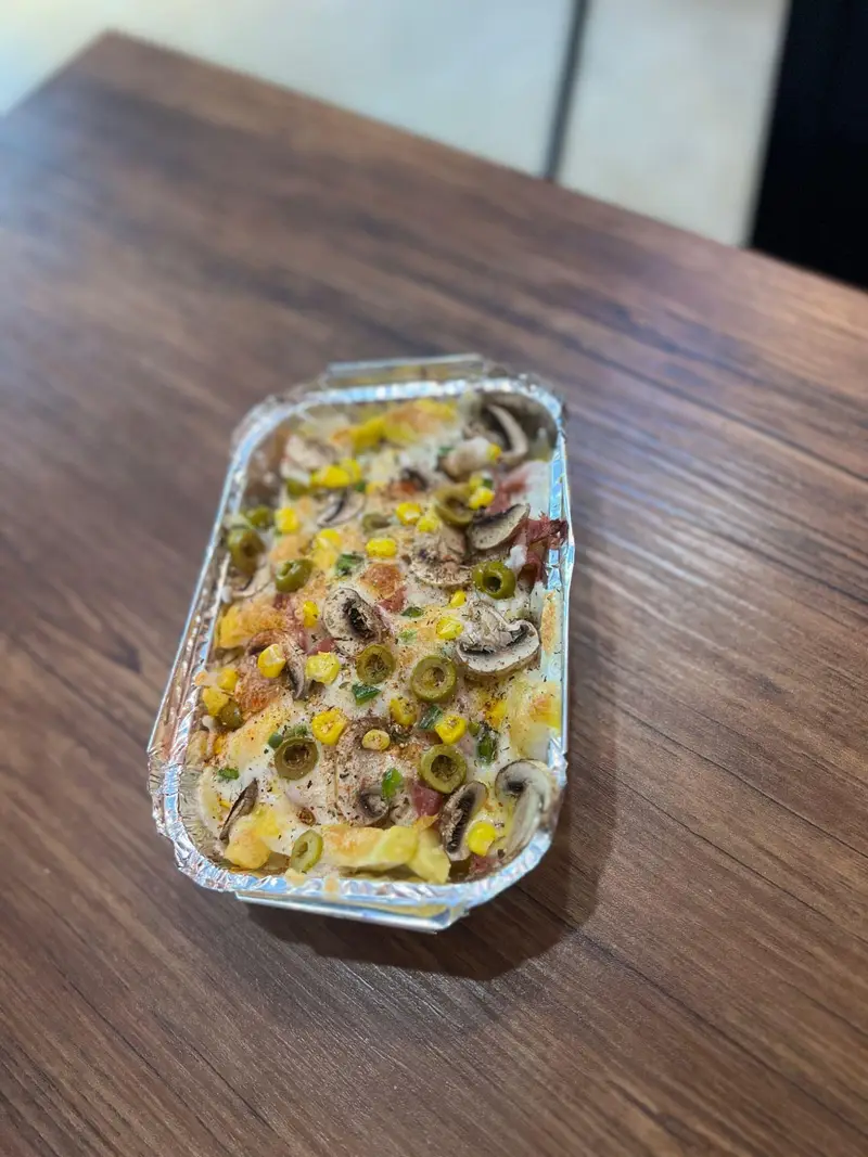 غذای گرم و لذیذ کافه پارس، ترکیبی از سیب‌زمینی پنیری با قارچ، زیتون، ذرت و تاپینگ‌های خوش‌رنگ در ظرف آماده.