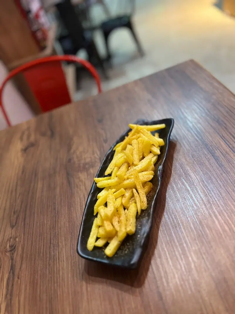 سیب زمینی سرخ کرده خوشمزه و تازه کافه پارس با چاشنی ادویه مخصوص، سرو شده روی میز چوبی در فضایی دلنشین و آرام.