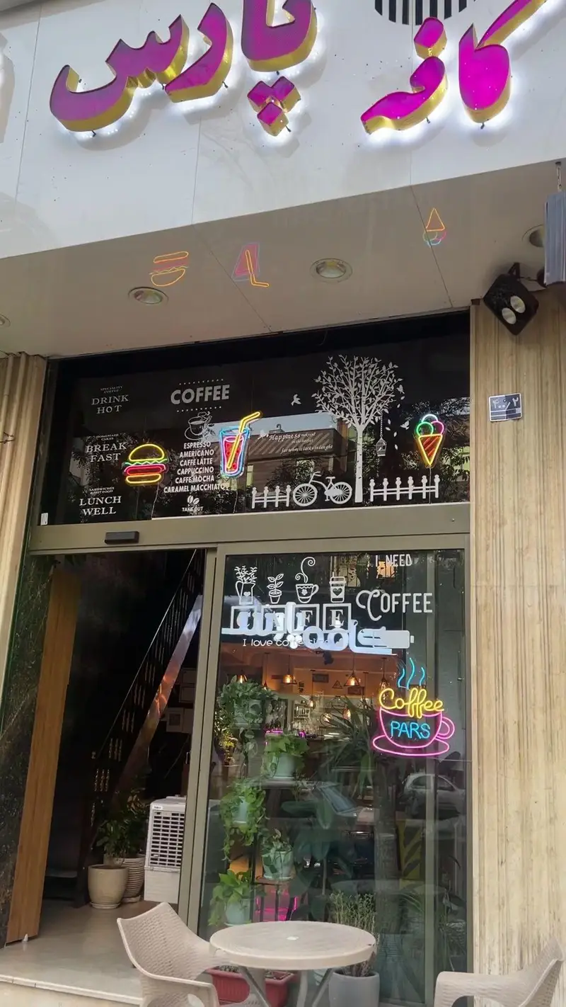 کافه پارس: ورودی جذاب با تابلوی نئون، منوی متنوع قهوه، صبحانه، ناهار، نوشیدنی‌ها و فضای سبز دلنشین برای پذیرایی.